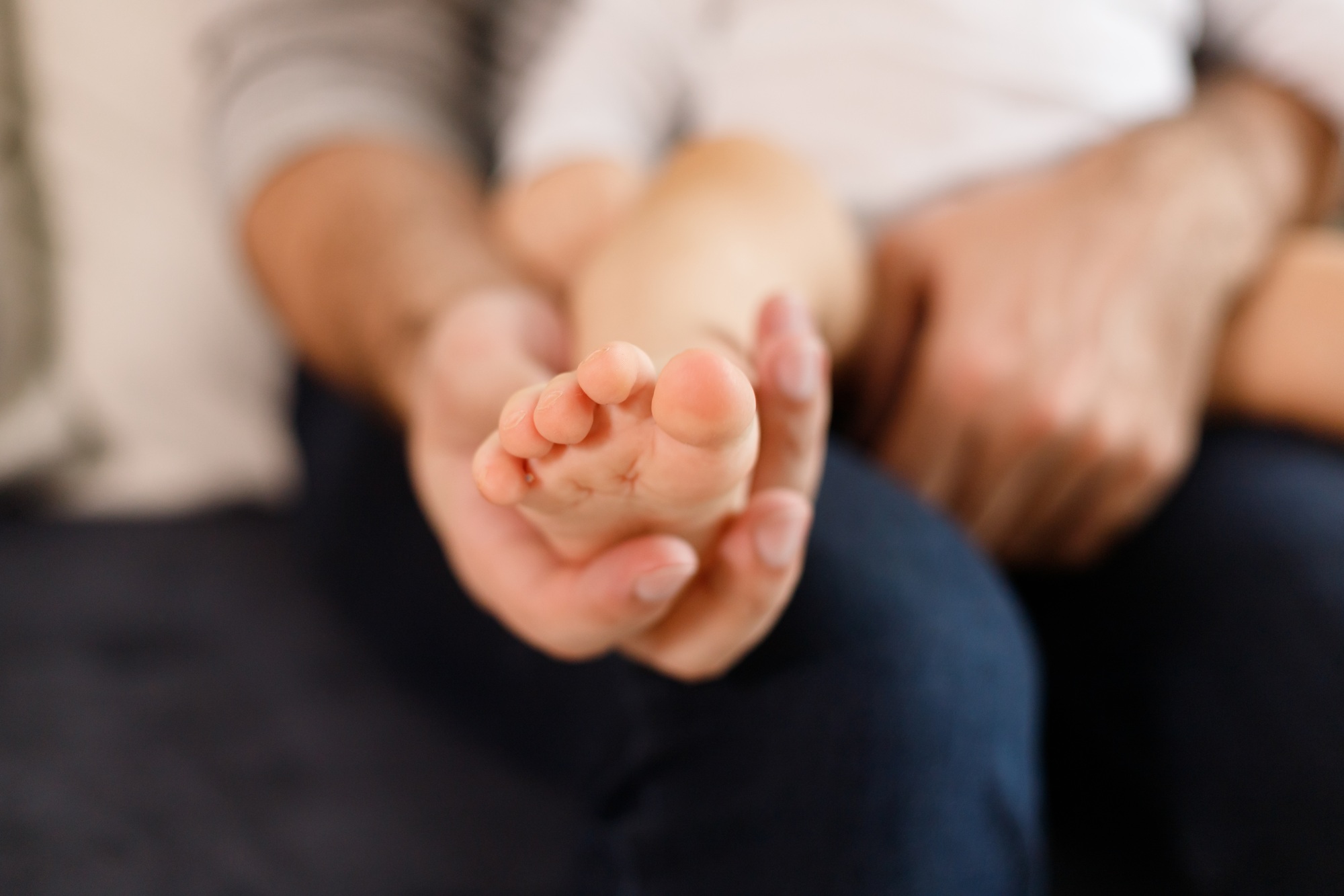 Pediatric Foot Care - Father's hands carefully keeping baby's foot with tenderness